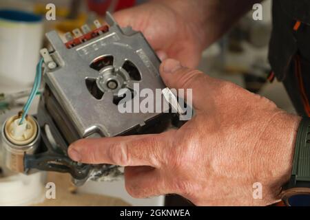 Repair Service Worker. Repairman is removing scale on the pomp of old dishwasher machine. Repair service concept. Dishwasher machine repair process. S Stock Photo