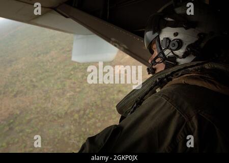 U.S. Marine Corps Cpl. Jason Willoughby, a crew chief with Marine Medium Tiltrotor Squadron 363 (Reinforced), Marine Rotational Force – Darwin, observes the terrain from the back of an MV-22B Osprey at Mount Bundey Training Area, NT, Australia, June 9, 2021. MV-22B Osprey pilots practiced touch-and-go’s and other tactical maneuvers throughout MBTA. The training hones the Marines’ capabilities as a skilled expeditionary fighting force that is capable of responding to a potential crisis or contingency. Stock Photo