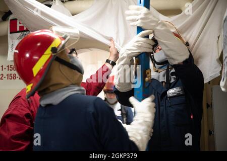 Sailors assigned to one of USS Gerald R. Ford's (CVN 78) repair lockers trains on proper shoring procedures during a general quarters drill, June 10, 2021. Ford is underway in the Atlantic Ocean conducting Full Ship Shock Trials (FSST). The U.S. Navy conducts shock trials of new ship designs using live explosives to confirm that our warships can continue to meet demanding mission requirements under harsh conditions they might encounter in battle. Stock Photo