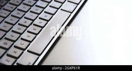 Detail of a modern white computer keyboard dirty and dusty on a white table. Computer hardware device. Technology and internet Stock Photo