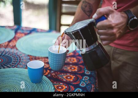 Man pouring coffee from a coffee maker into a cup Stock Photo