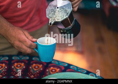 Man pouring coffee from a coffee maker into a cup Stock Photo