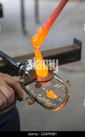 Glassblower cuts molten glass with a hand tool Stock Photo