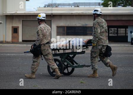 Members of the California National Guard search and extraction team transport a patient on a gurney to a casualty collection point during a joint exercise in Kapolei, Hawaii, June 16, 2021. Search and extraction teams trained on how to extract patients from damaged buildings in a simulated hurricane scenario. Stock Photo
