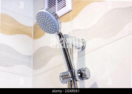 New shiny metal shower head on ceramic tile wall background in the bathroom. Stock Photo