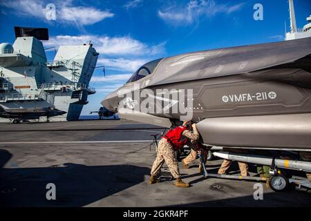U.S. Marines with Marine Fighter Attack Squadron (VMFA) 211, Carrier Strike Group (CSG) 21, load an AIM-120 Advanced Medium-Range Air-to-Air Missile into an F-35B Lightning II aboard HMS Queen Elizabeth in 6th Fleet Area of Operations on June 18th, 2021. Alongside the United Kingdom’s 617 Squadron, VMFA-211 is conducting combat sorties in support of Operation Inherent Resolve (OIR), the first combat operations launched from HMS Queen Elizabeth. OIR is the operation to eliminate the ISIL terrorist group and the threat they pose to Iraq, Syria, and the wider international community.