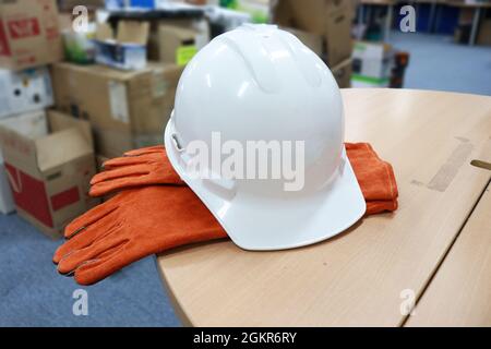 White safety helmet to protect workers' heads from work accidents, such as collisions with hard objects, leather gloves to protect hands, Stock Photo