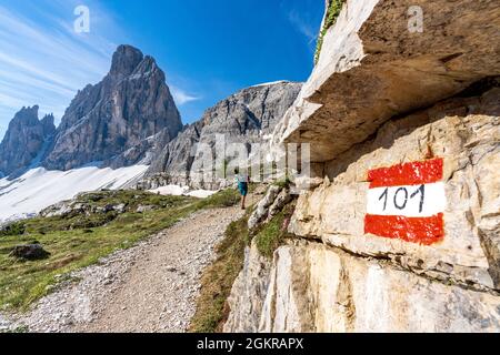 Rear view of hiker woman walking on path to majestic Croda Dei Toni mountain, Sesto Dolomites, South Tyrol, Italy, Europe Stock Photo