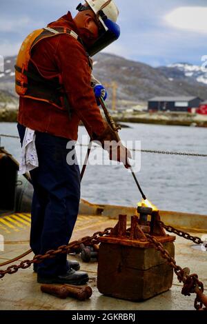 The USCGC Maple (WLB 207) crew member welds on the buoy deck in Greenland, June 18, 2021.  Deployed forces demonstrated U.S. Coast Guard capabilities to build partner capacity and expertise in search and rescue, incident management, and marine environmental response. These efforts solidify key strategic relationships while achieving mutual Danish, Greenlandic, and U.S. goals in the North American Atlantic Arctic and Northwest Atlantic Ocean. Stock Photo