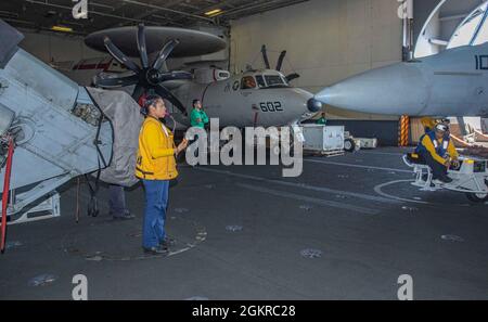210619-N-NY362-1050 ANDAMAN SEA (June 19, 2021) Aviation Boatswain’s Mate (Handling) Airman Glenda Chavarria, from Las Vegas, directs the movement of an F/A-18F Super Hornet attached to the Diamondbacks of Strike Fighter Squadron (VFA) 102 in the hangar bay of the U.S. Navy’s only forward-deployed aircraft carrier USS Ronald Reagan (CVN 76). Ronald Reagan, the flagship of Carrier Strike Group 5, provides a combat-ready force that protects and defends the United States, as well as the collective maritime interests of its allies and partners in the Indo-Pacific region. Stock Photo
