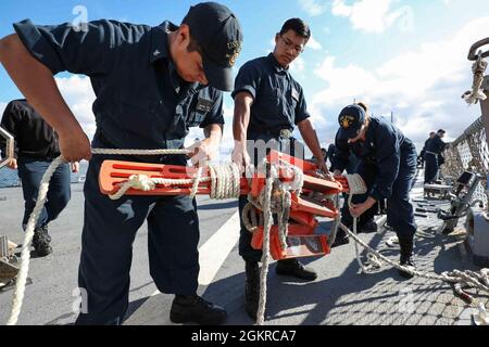 ROTA, Spain (June 19, 2021) Sonar Technician (Surface) 3rd Class Jonathan Salas, left, Fire Controlman (Aegis) 3rd Class Arthur Cataag, center, and Sonar Technician (Surface) 2nd Class Paige Jewett, assigned to the Arleigh Burke-class guided-missile destroyer USS Ross (DDG 71), prepare a pilot ladder to be stowed after leaving port at Naval Station Rota, Spain, June 19, 2021. Ross, forward-deployed to Rota, Spain, is on patrol in the U.S. Sixth Fleet area of operations in support of regional allies and partners and U.S. national security interests in Europe and Africa. Stock Photo