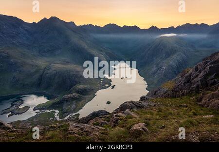 The sun setting behind the Black Cuillin Ridge with the remote Loch Coruisk in the glen below, Isle of Skye, Inner Hebrides, Scotland, United Kingdom Stock Photo
