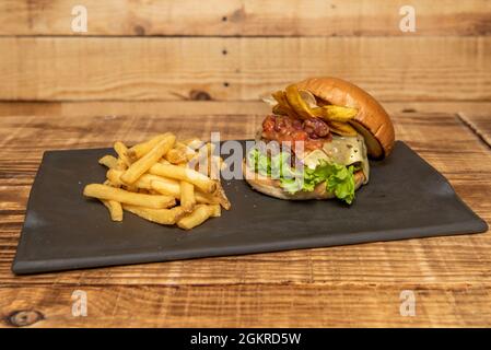 Mexican-style beef burger with banana chips, melted cheese, spicy bean chili and lettuce with fries Stock Photo