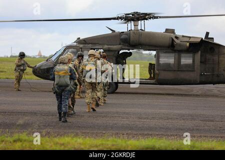 Brazilian Marine Corps (BMC) Cmdr. Gustavo Soares Gomes with BMC  Headquarters is assisted by a U.S. Soldier with 3rd Battalion, 7th Special  Forces Group before parachute training during Tradewinds 2021, Air Station