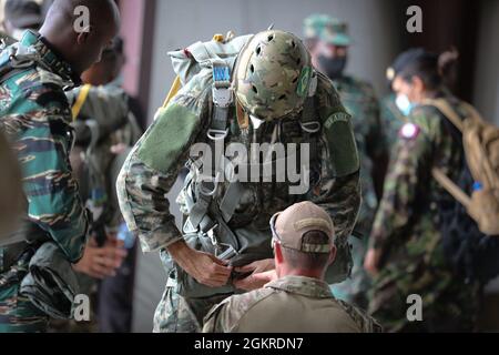 Brazilian Marine Corps (BMC) Cmdr. Gustavo Soares Gomes with BMC  Headquarters is assisted by a U.S. Soldier with 3rd Battalion, 7th Special  Forces Group before parachute training during Tradewinds 2021, Air Station