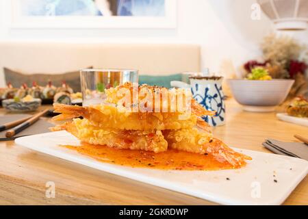 Fried panko flour battered prawns served on the table of a Japanese restaurant with light wooden tables Stock Photo