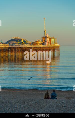 View of couple on beach and Brighton Palace Pier at sunset, Brighton, East Sussex, England, United Kingdom, Europe Stock Photo