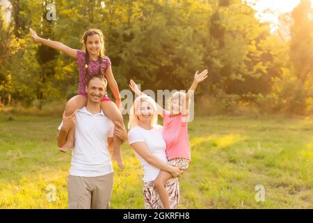 Happy family walking in field and looking at sunset Stock Photo