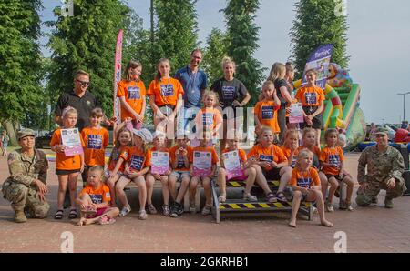 Army Pfc. Rebekah Rodriguez (far left) and Spc. Nicki Myers (far right), medics deployed with the Pennsylvania Guard’s 108th Medical Company Area Support, pose with local children and dancers from Skakanka Dance & Fitness during a community event in Powidz, Poland, on June 21, 2021. Stock Photo