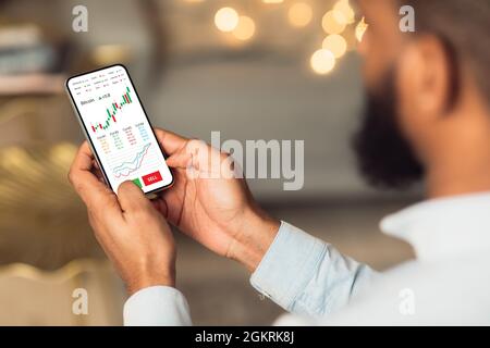 Relaxed black businessman checking bitcoin price on cellphone Stock Photo