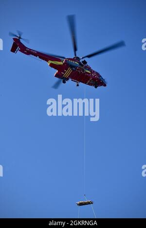 The USCGC Maple (WLB 207) crew participate in a hoisting exercise with a local helicopter air crew, near Greenland, June 22, 2021. Deployed forces demonstrated U.S. Coast Guard capabilities to build partner capacity and expertise in search and rescue, incident management, and marine environmental response. These efforts solidify key strategic relationships while achieving mutual Danish, Greenlandic, and U.S. goals in the North American Atlantic Arctic and Northwest Atlantic Ocean. Stock Photo