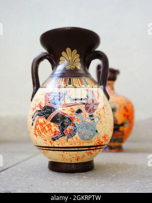 Vertical shot of two Greek vases with drawings isolated on the paved floor Stock Photo