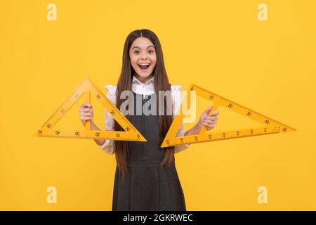 child with triangle. angle degree measurement. surprised teen girl hold ruler. back to school. Stock Photo