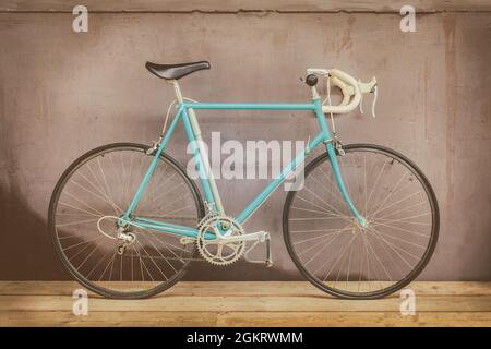 Vintage seventies light blue racing bicycle on a wooden floor with a weathered background wall Stock Photo
