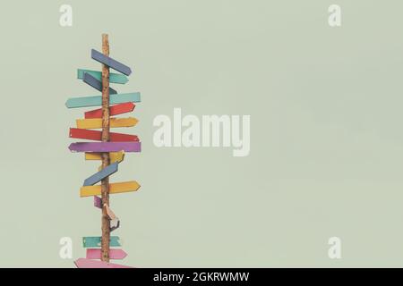 Retro styled image of colorful wooden direction arrow signs on a wooden pole Stock Photo