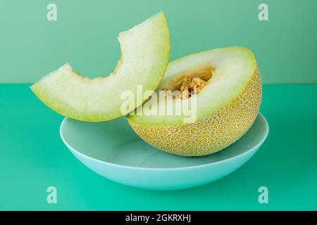 Half yellow melon with seeds and a cut and clean portion of seeds on a blue deep plate Stock Photo