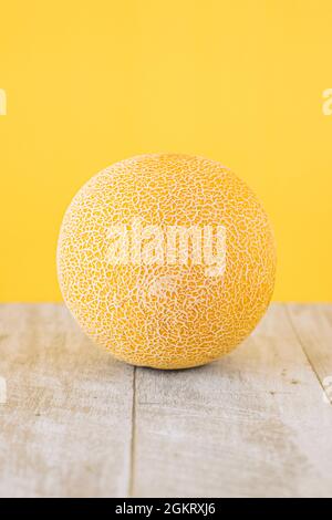 Yellow Galia melon on wooden table and yellow background Stock Photo