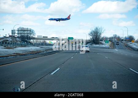 Sun Country airplane in flight over Highway 5, approaching the apron of the Minneapolis St Paul International airport.  Bloomington Minnesota MN USA Stock Photo