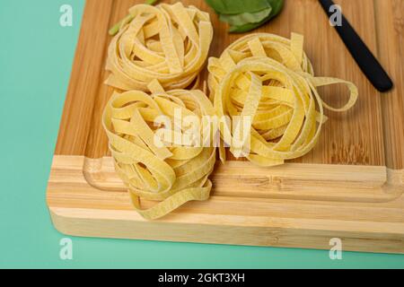 Italian fresh pasta nests on a bamboo table and green background Stock Photo