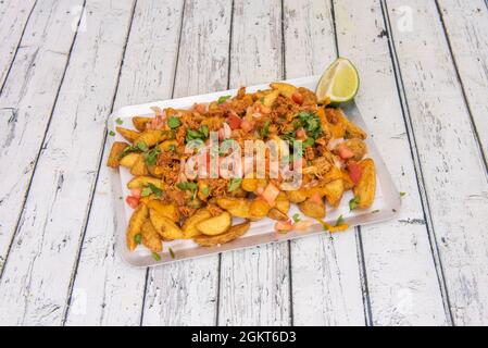 French fries in wedges with pull chicken, pico de gallo and lots of chopped parsley with lime juice Stock Photo