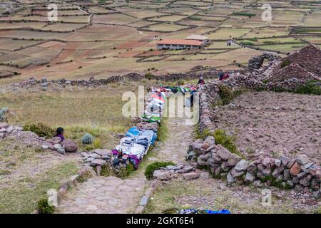 AMANTANI, PERU - MAY 15, 2015: Locals sell hand made products at the path leading to Pachamama hill on Amantani island in Titicaca lake, Peru Stock Photo