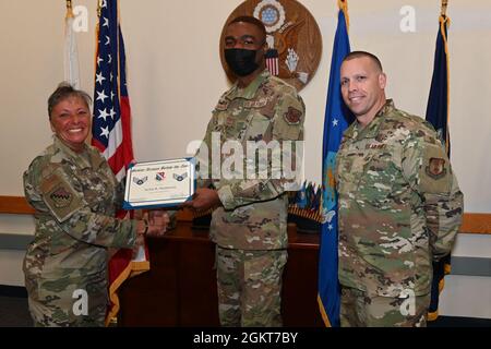Col. Katrina Stephens, installation commander, and Chief Master Sgt. William Hebb, installation command chief, present Airman 1st Class Jachin Henderson, Joint Personal Property Shipping Office-Northeast Shipment Distribution technician, with a promotion to senior Airman, below the zone, at Hanscom Air Force Base, Mass., June 25. Below the Zone is a competitive early promotion that recognizes top performers. Stock Photo