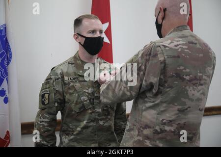 Maj. Gen. John P. Sullivan, commanding general, 1st Theater Sustainment Command, pins the Army Commendation Medal on Maj. Timothy Ladwig, aide de camp, 1st Theater Sustainment Command, during a frocking ceremony at Camp Arifjan, Kuwait, June 26, 2021. Ladwig will be a part of the Blue Team during his time at Camp Afrijan. Stock Photo