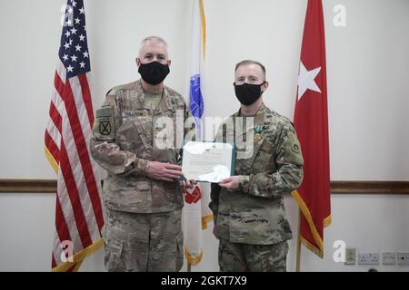 Maj. Gen. John P. Sullivan, commanding general, 1st Theater Sustainment Command, presents the Army Commendation Medal certificate to Maj. Timothy Ladwig, aide de camp, 1st Theater Sustainment Command, during a frocking ceremony at Camp Arifjan, Kuwait, June 26, 2021. Ladwig will be a part of the 1st TSC Plans Team during his time at Camp Afrijan. Stock Photo