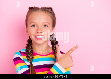 Photo of cute lovely little lady direct finger empty space wear striped shirt isolated pink color background Stock Photo