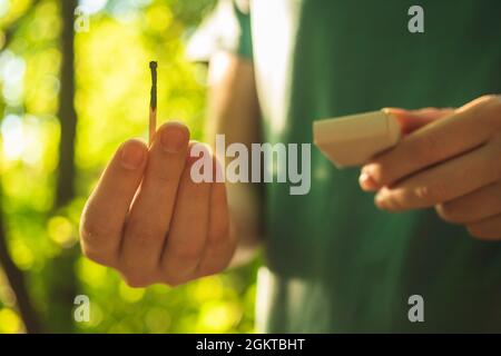 Children hands with burning match in the dry forest. Danger of forest fire, environment disaster concept Stock Photo