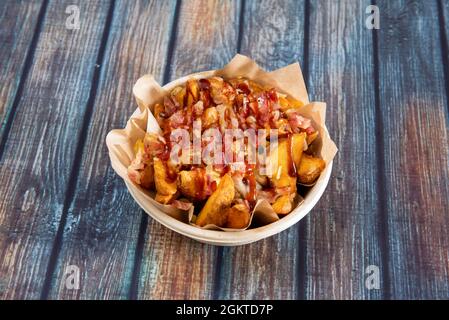 Popular recipe for potato wedges fried in their own skin with lots of fried bacon chopped into tacos and plenty of barbacoa sauce cooked in a home del Stock Photo