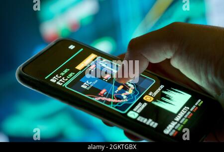 A businessman checking cryptocurrency and stock prices on a mobile app. Investing using a smartphone online. Stock Photo