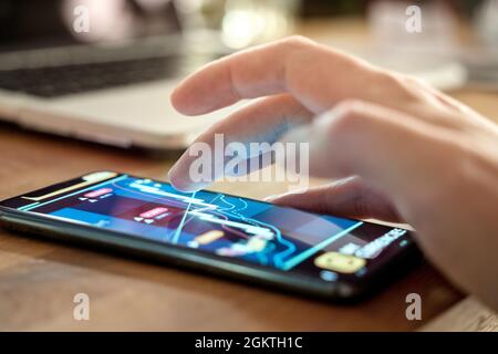 A man at home using a smartphone to check his stocks and investments. Trading and investing on the go using current technology. Generic trading chart Stock Photo