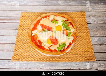 Spanish pizza with broken eggs recipe as a tapa with fried eggs, Iberian ham and Manchego cheese Stock Photo