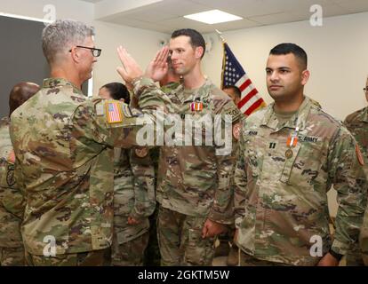 SINAI PENINSULA, Egypt - Col. Scott Sentell (left), the brigade commander of Task Force Sinai, returns a salute to Capt. John Bates (center), the current commander of Explosive Ordnance Detachment, Task Force Sinai, as Capt.       Hamzah Kahn (right), the Task Force Sinai legal officer looks at an end of tour ceremony held at the South Camp, South Sinai, Egypt June 30, 2021. Stock Photo