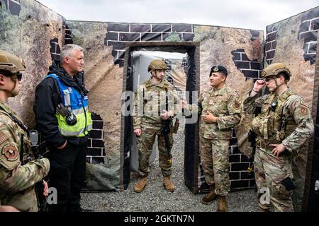 Staff Sgt. Carlos Sandoval, center right, 422nd Security Forces Squadron unit trainer, speaks with John Hogg, center left, Northamptonshire Police Department firearms instructor, following a tri-agency active shooter response exercise at RAF Croughton, England, June 30, 2021. Airmen from the 422nd SFS along with police officers from the NHPD and Ministry of Defense, participated in multiple exercises to enhance their search and seizure tactics, strengthen local ties and gain rapport with their fellow officers. Stock Photo