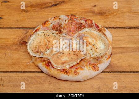 Mini pizza with melted goat cheese as the main ingredient and drizzled with oregano on wooden board