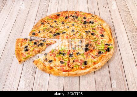 Delicious four seasons Italian pizza recipe with black olives, green peppers, chopped smoked bacon, sliced mushrooms and melted cheese Stock Photo