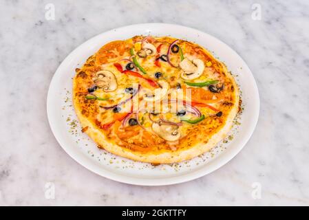 Vegetable pizza for one person with mushrooms, roasted tomato, green and red peppers, red onion, black olives and wheat dough Stock Photo