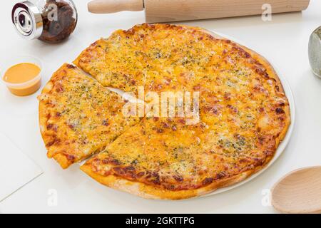 delicious four cheese pizza with a slice cut ready to give you a wild and eager bite on white plate Stock Photo